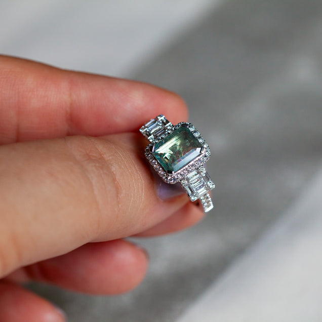 Detailed view of a 2.23ct alexandrite stone in an 18k white gold ring setting held by a person