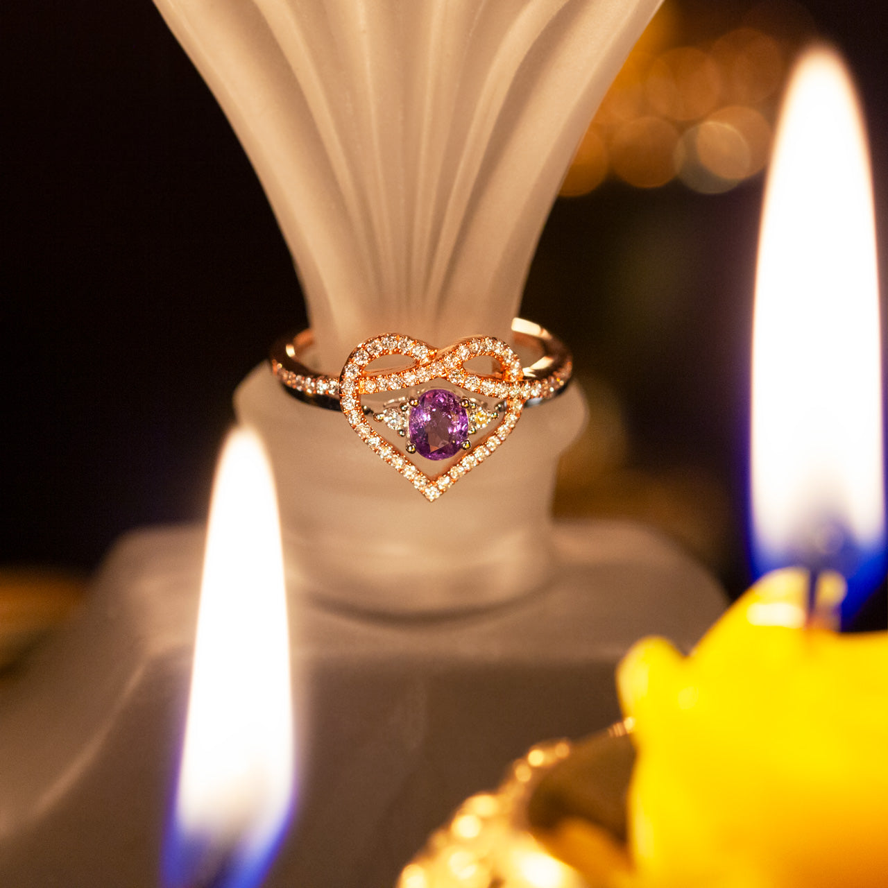 18k white and rose gold heart-shaped ring set with natural alexandrite and diamonds illuminated by candlelight