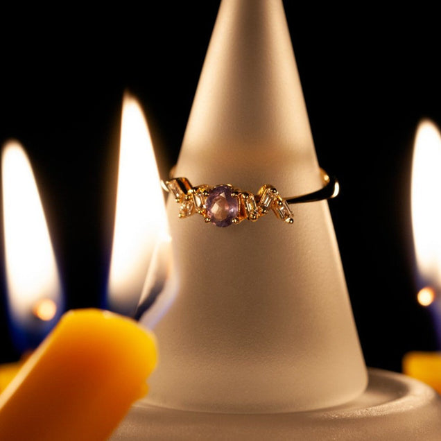 A 0.33ct natural Alexandrite ring on an 18K yellow gold band displayed on a candle