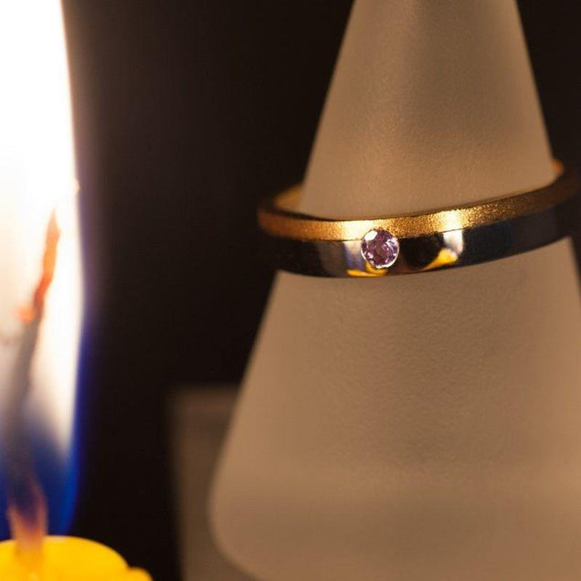 Natural alexandrite two-toned 18k gold wedding band showcased on a plain background