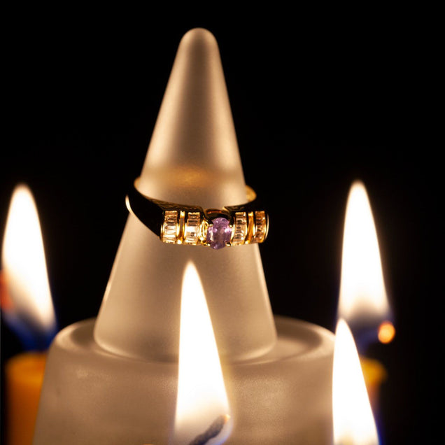 The 18k yellow gold unisex ring with a 0.37ct alexandrite stone displayed atop a candle