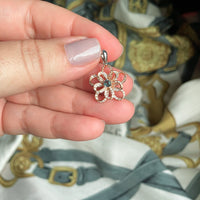 Thumbnail for Hand holding a delicate 0.18ct natural alexandrite flower pendant in 18k rose and white multitone gold with diamond accents