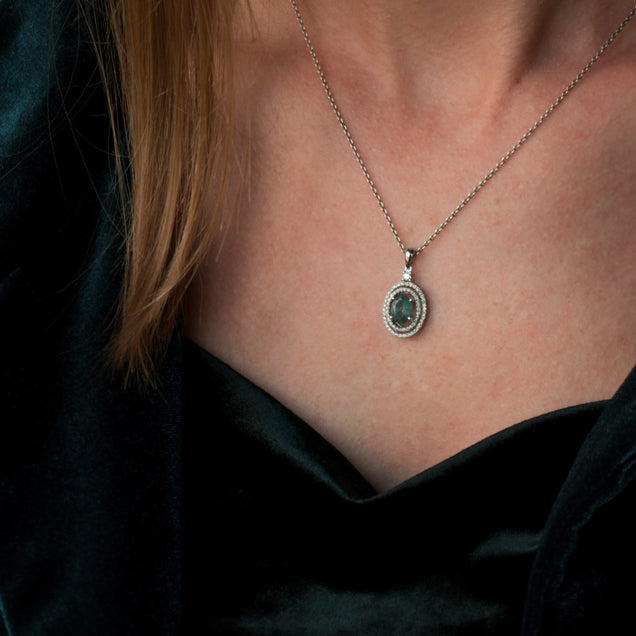 A woman displaying a 1.35ct natural Alexandrite 18k white gold pendant around her neck