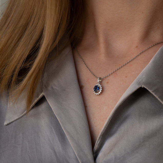 Elegant 18k white gold necklace with a 0.73ct blue sapphire and diamond pendant worn by a woman