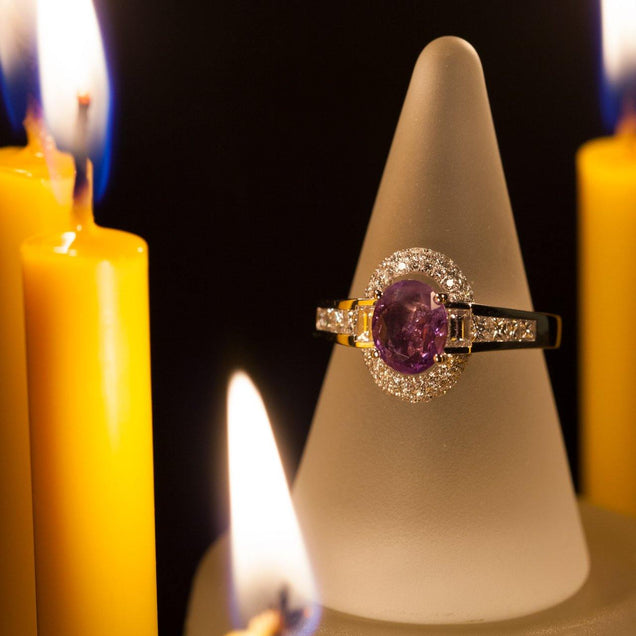 An 18k gold ring with a 1.00ct alexandrite stone displayed on a candle