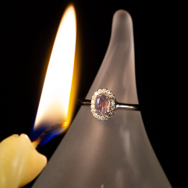 18k white gold ring with 0.42ct natural alexandrite displayed on a candle
