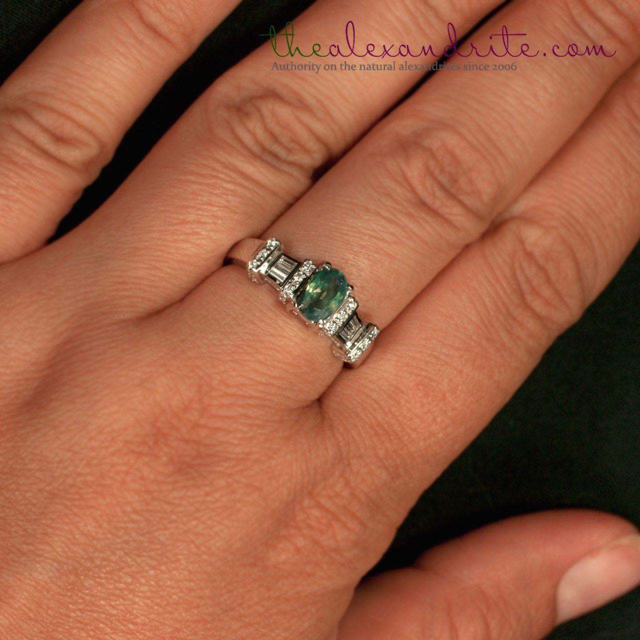 Hand wearing a 1.11ct alexandrite ring in 18K white gold showing green hue