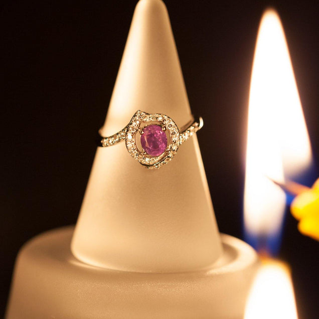 A 1.14ctw natural alexandrite ring in 18k gold, elegantly resting on a candle with a focus on the stone's unique hue