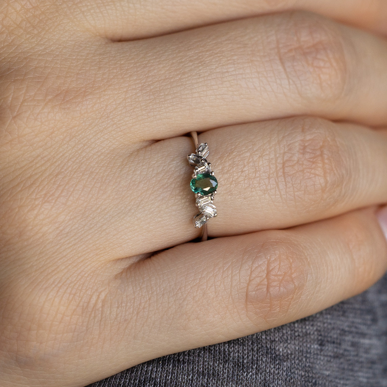 Close-up of a hand wearing a delicate 0.25ct natural alexandrite and diamond 18k white gold stackable ring