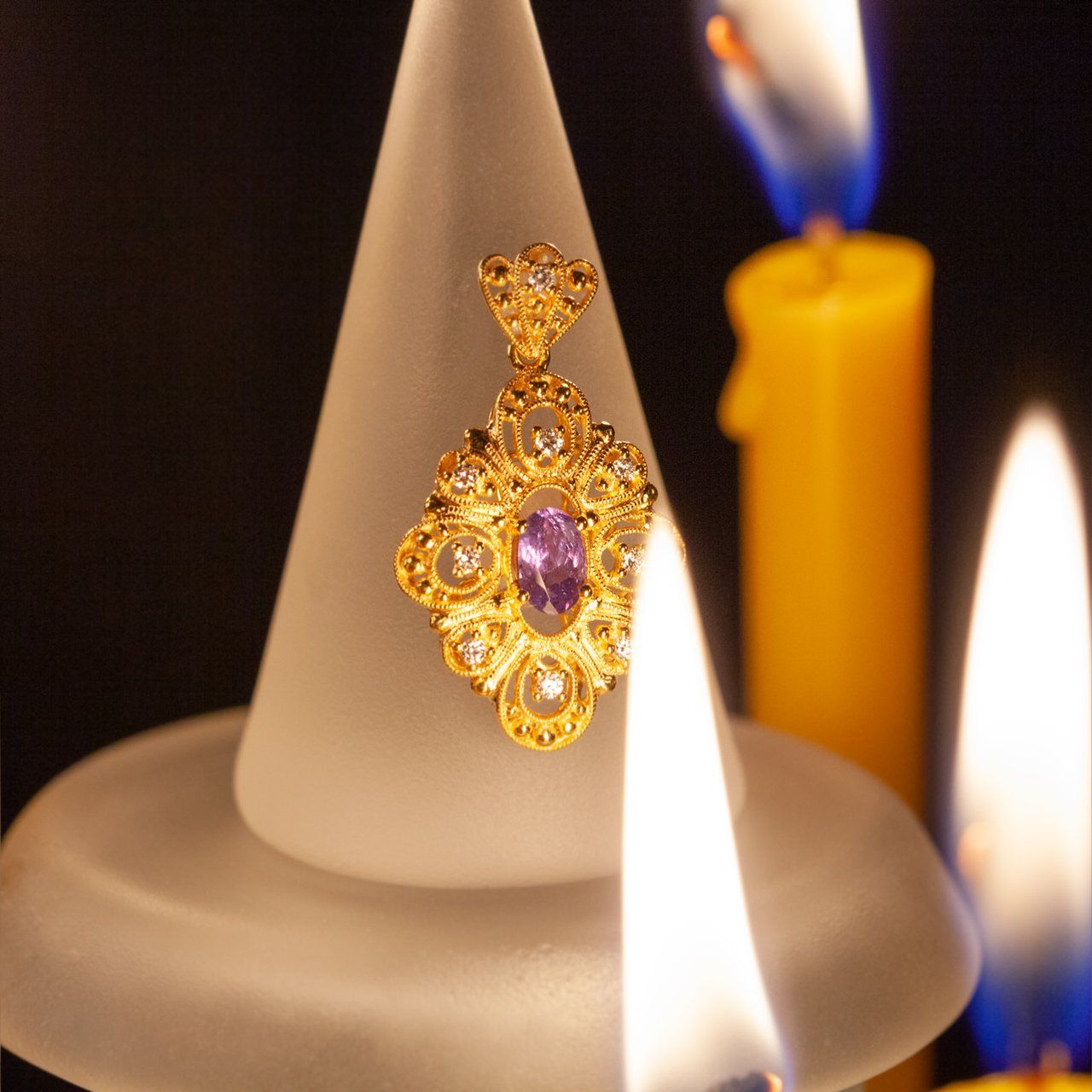 0.30ct alexandrite set in an 18k yellow gold pendant displayed on a candle