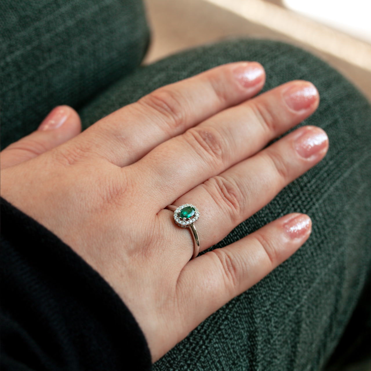 Close-up of a woman's hand wearing an 18k white gold Alexandrite ring with diamond halo