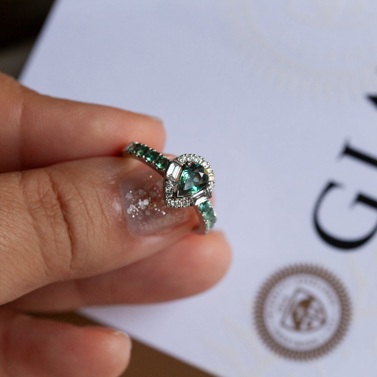 Natural alexandrite platinum ring with pear-shaped center stone, surrounded by diamonds and accented with round alexandrites on band.
