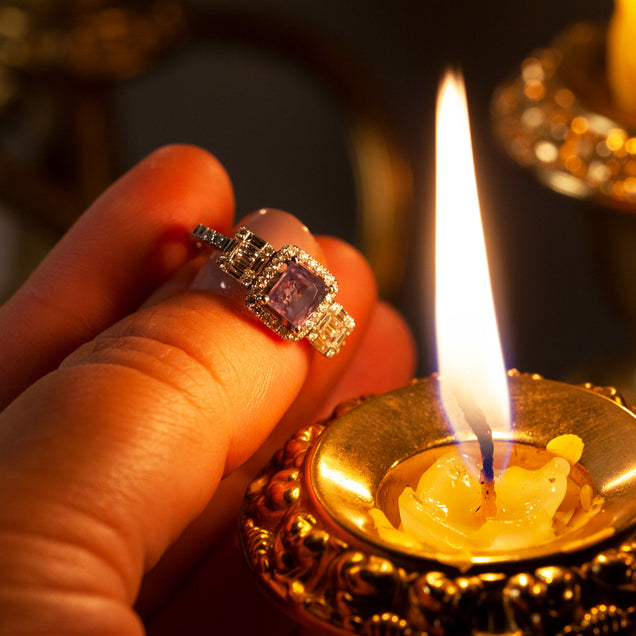 A woman's hand presenting a 1.17ct natural Alexandrite ring set in 18k white gold with a candle in the background