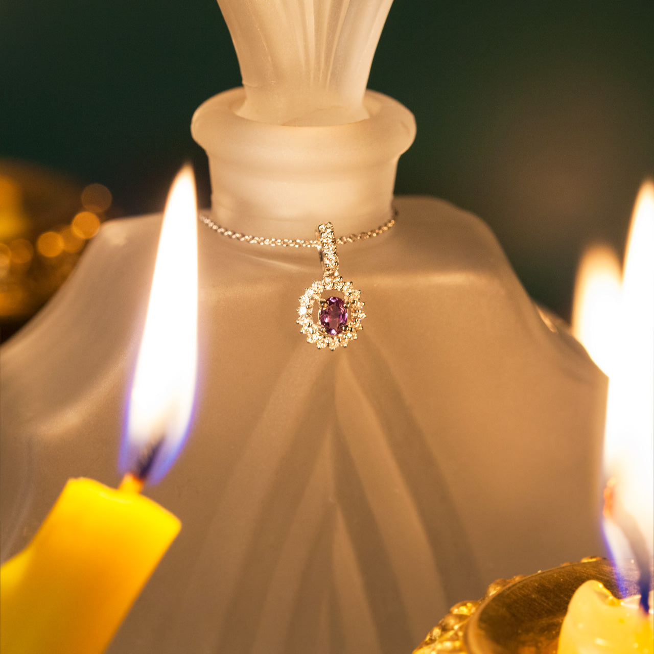 Candlelight reflecting off a 0.20ct alexandrite stone set in an 18k white gold pendant