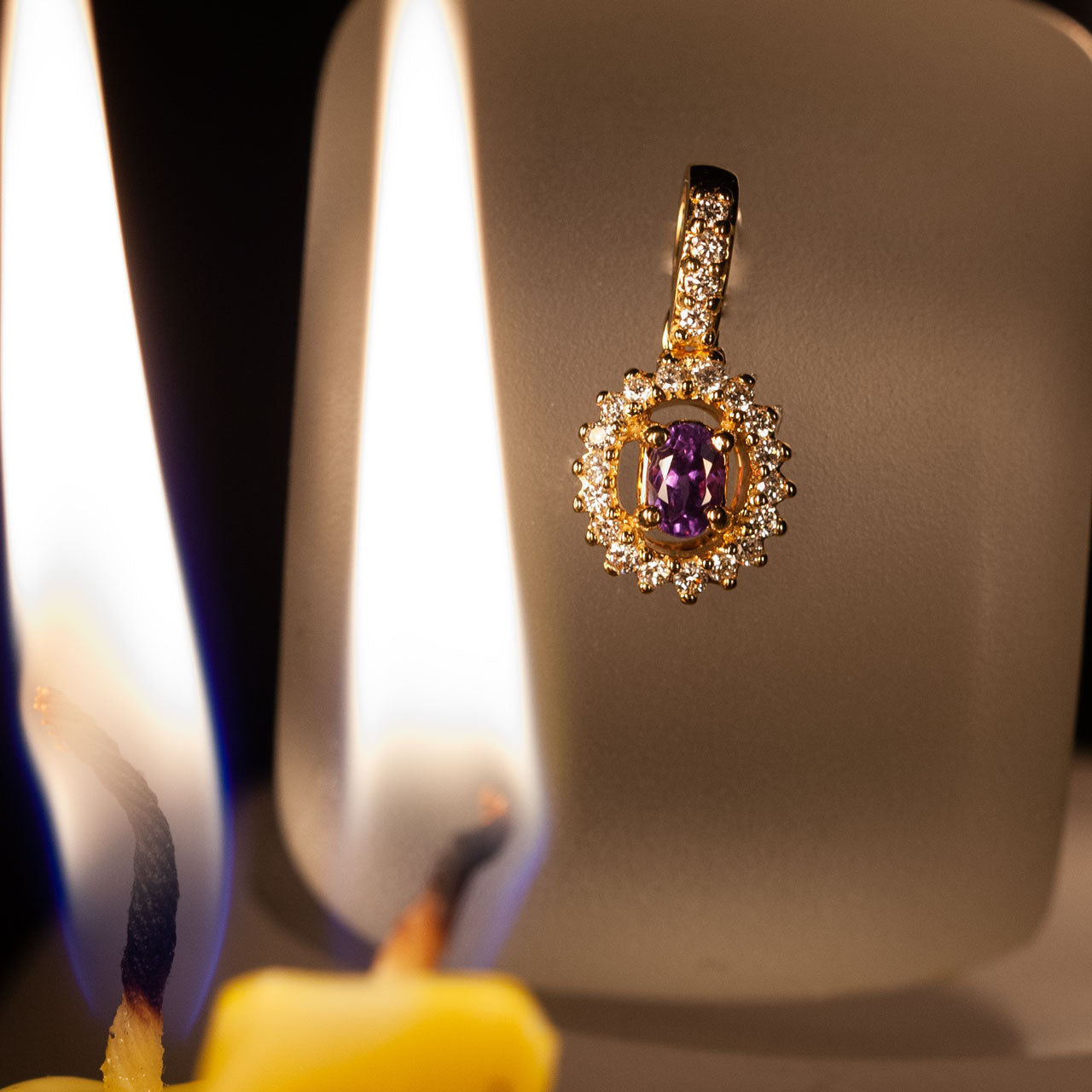 18k yellow gold pendant featuring a 0.23ct Alexandrite stone with candlelight in the background