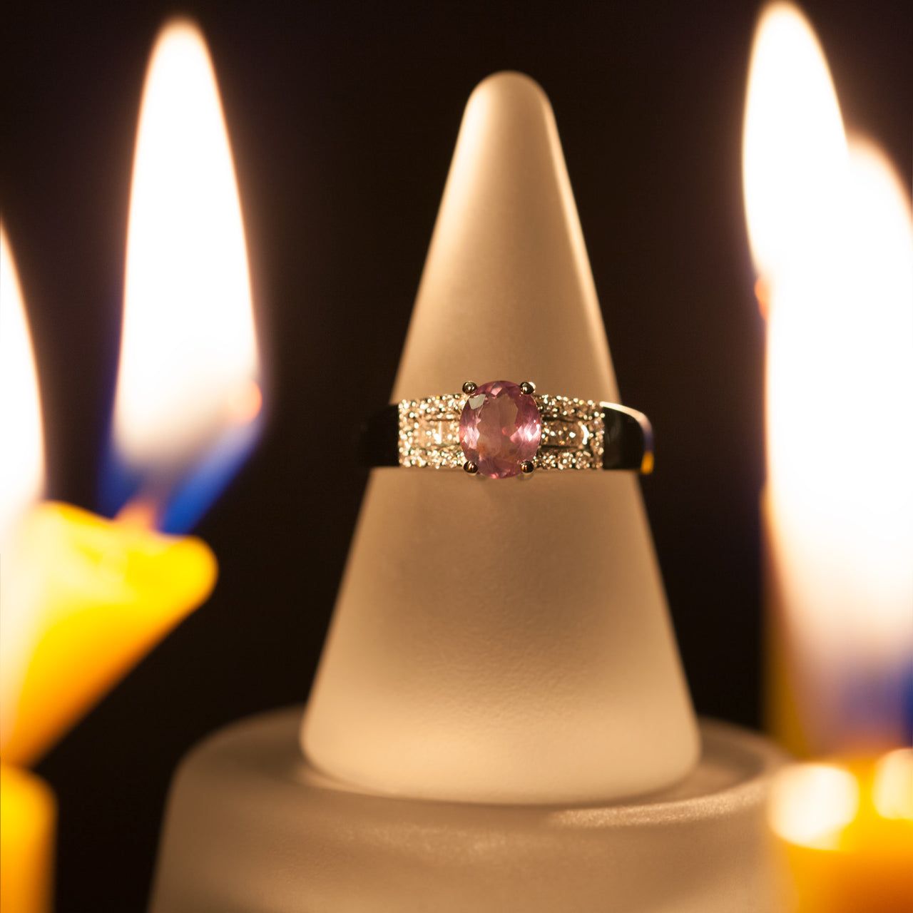 18k white gold ring with a 1.22ct alexandrite that appears pink in color, displayed on a candle