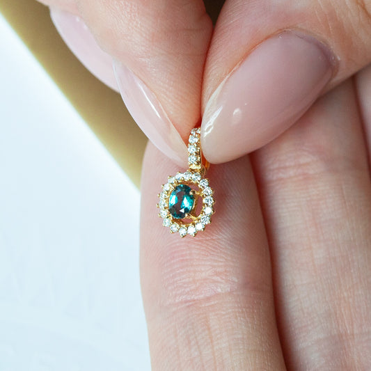Close-up of a 0.22ct natural Alexandrite pendant in 18k yellow gold held by a person
