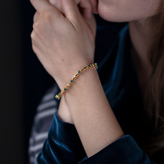 A woman showcasing the 3.00ctw natural alexandrite 18k yellow gold bracelet paired with green bead accessories