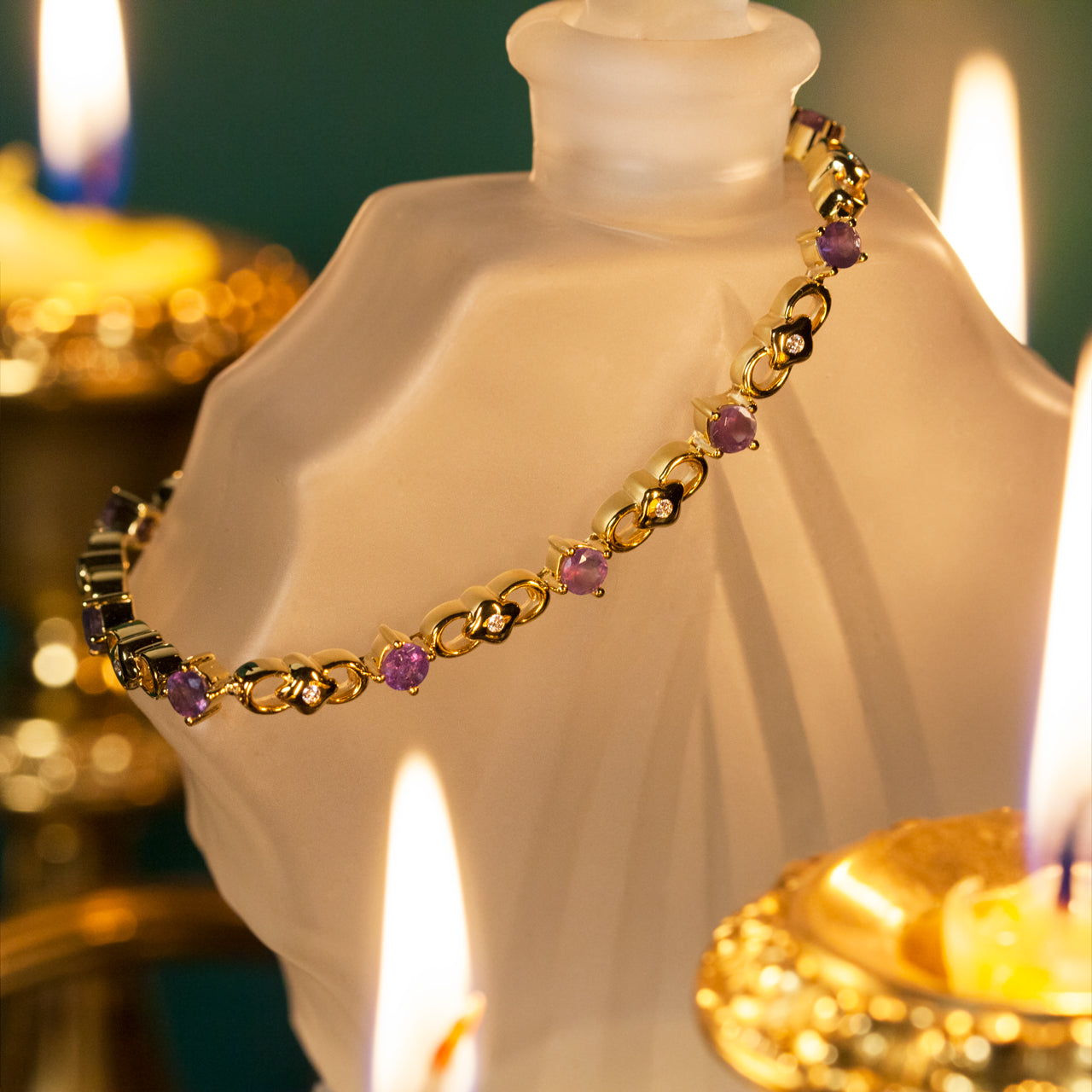 The 3.00ctw natural alexandrite 18k yellow gold bracelet elegantly presented next to a lit candle and decorative bottle