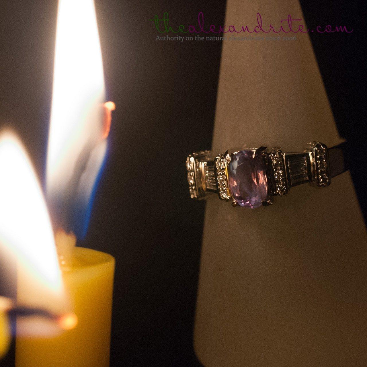 Alexandrite and 18K white gold ring displaying color change next to a candle