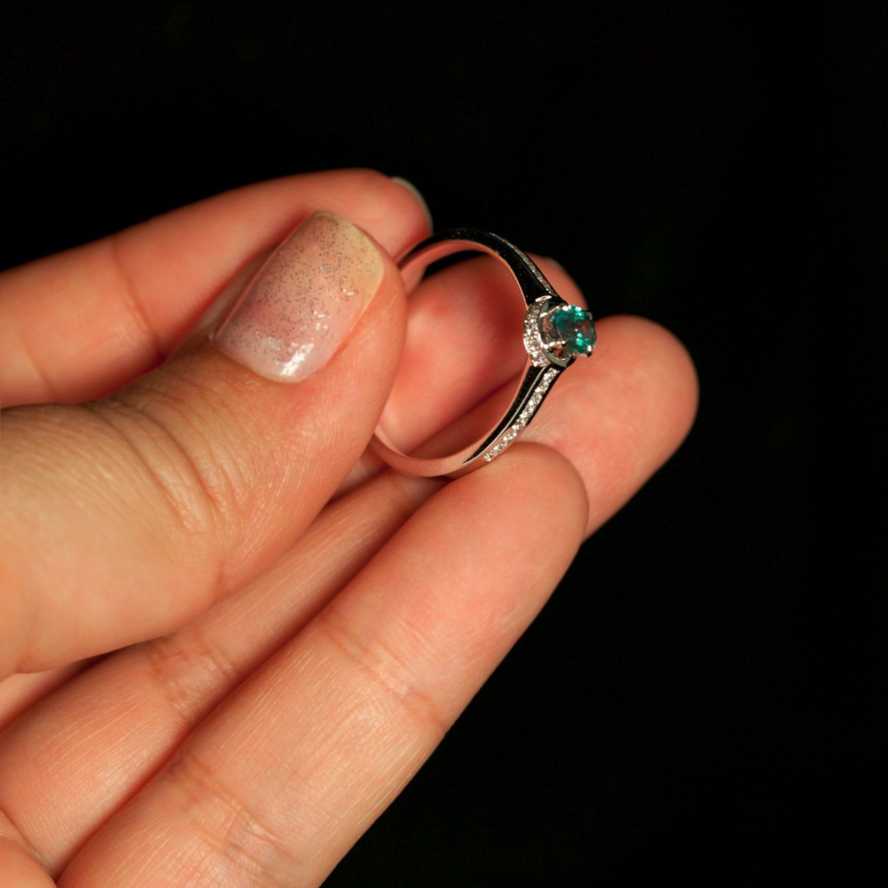 Hand showcasing a 0.55ct blue to green color-changing alexandrite ring in 18k white gold