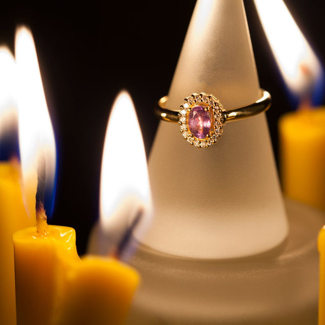 The 0.55ct natural alexandrite stone on an 18k yellow gold ring, showcased on a candle to highlight its unique color shift