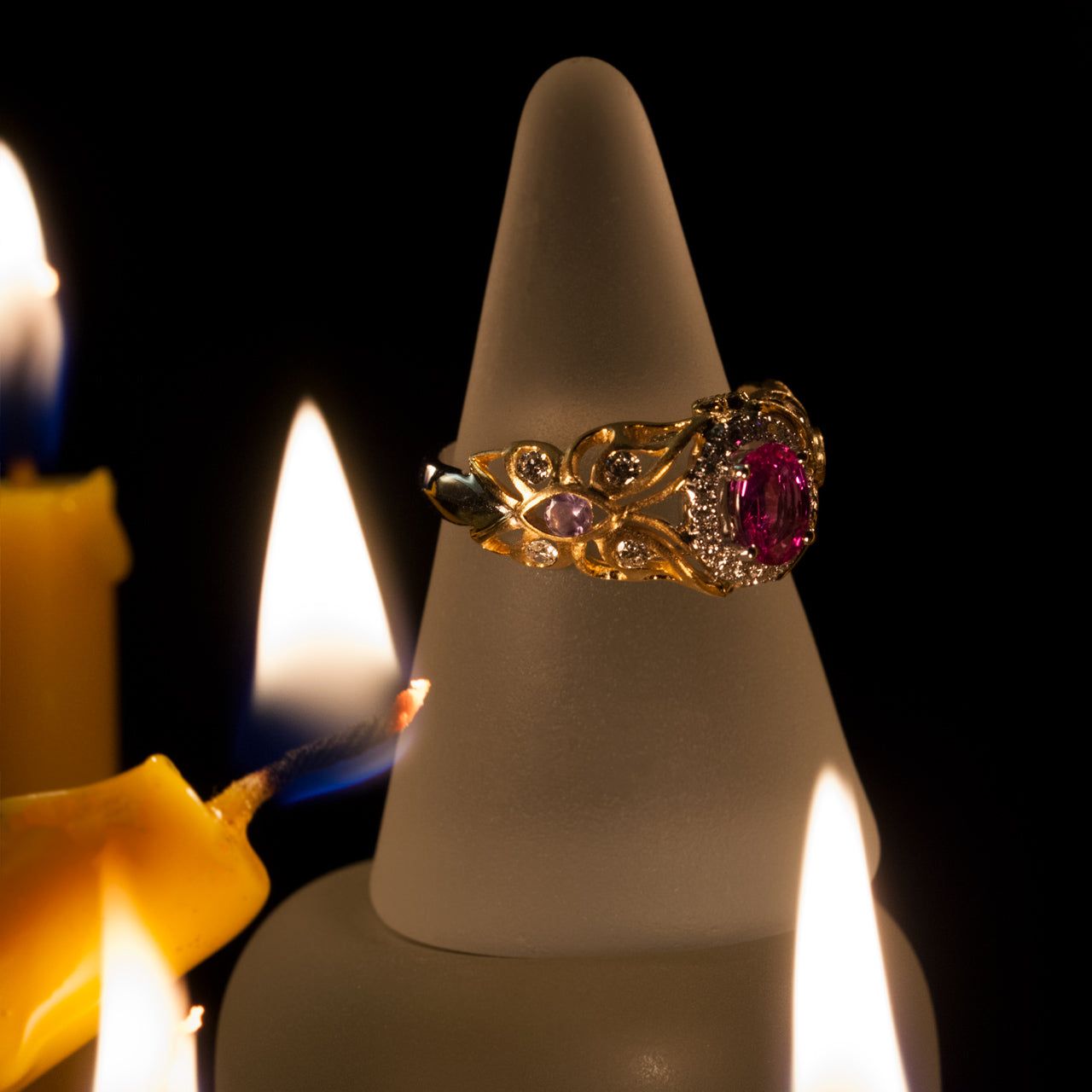 0.74ct pink sapphire ring in 18k gold setting displayed on a candle for ambiance