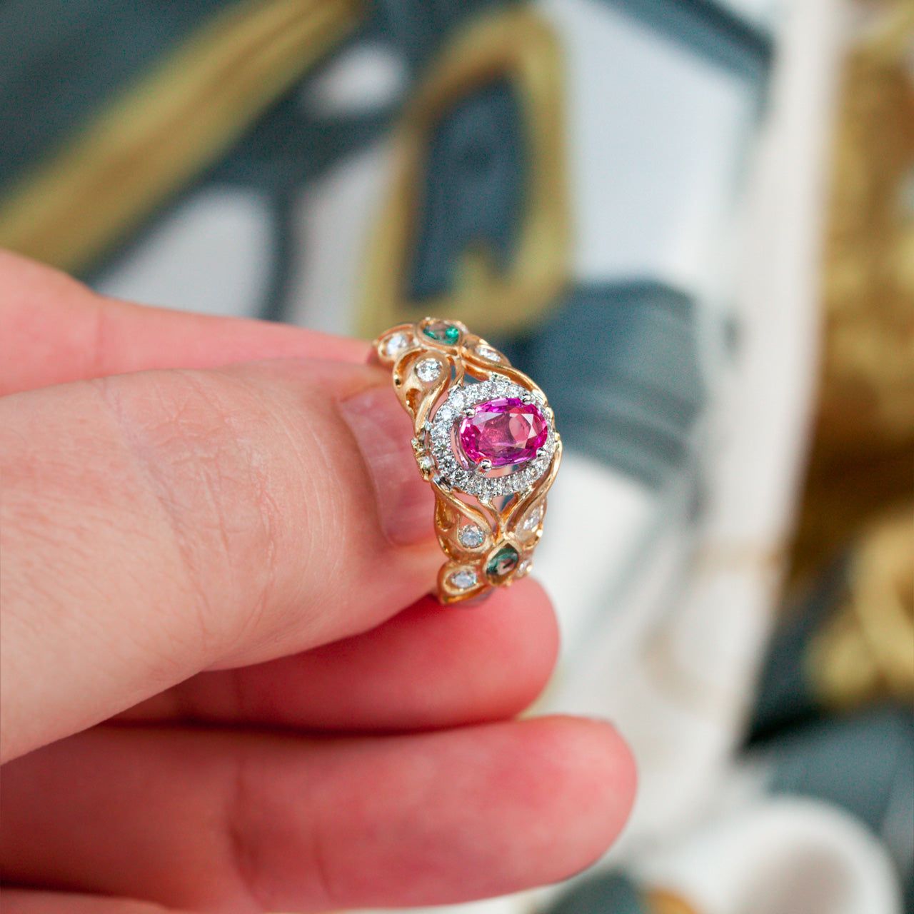 Hand holding a luxurious 0.74ct pink sapphire ring with alexandrite side stones set in 18k gold