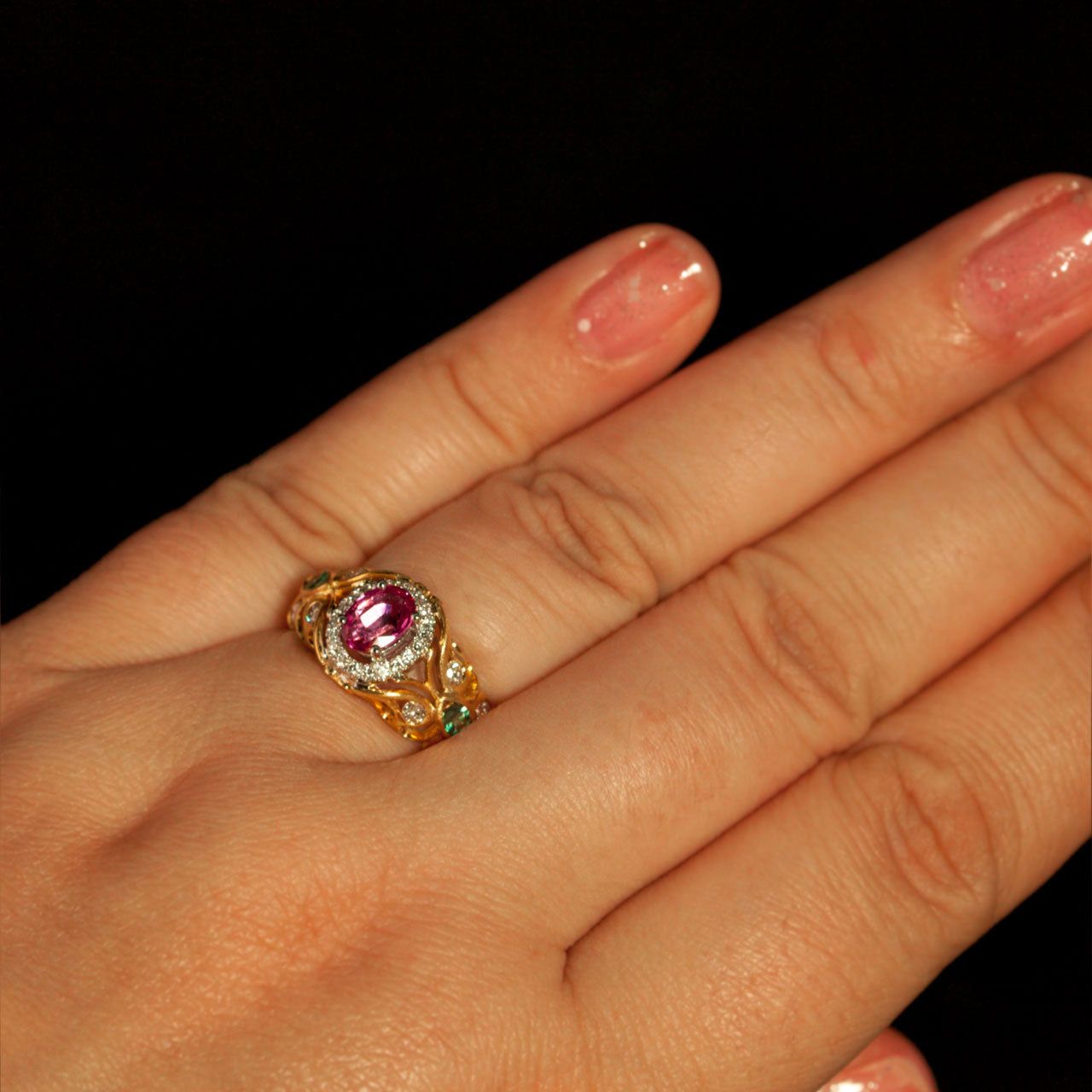 A woman's hand elegantly displaying a 0.74ct pink sapphire ring with 18k gold and alexandrite accents