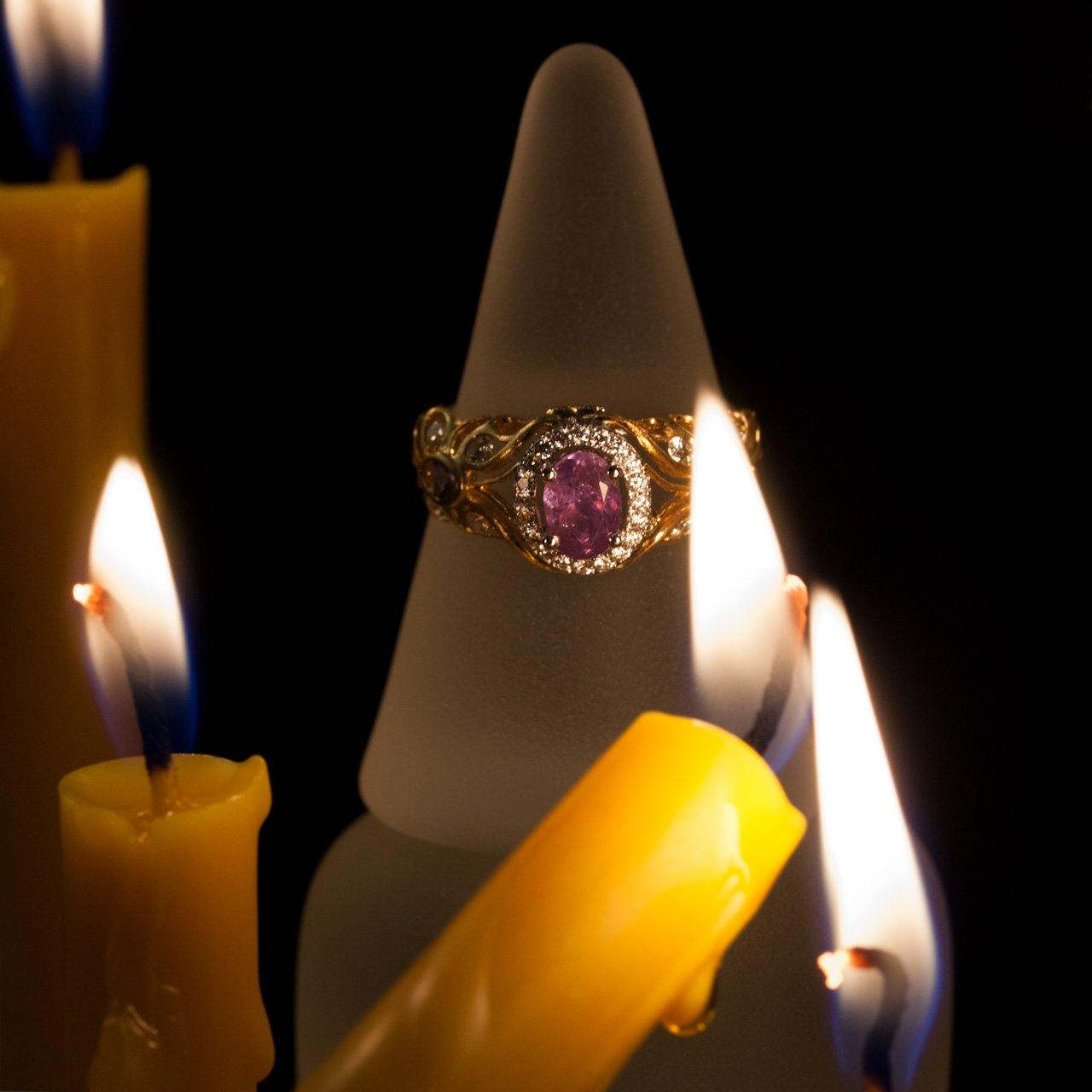 0.67ct natural Alexandrite 18k two-tone gold filigree ring placed beside a decorative candle