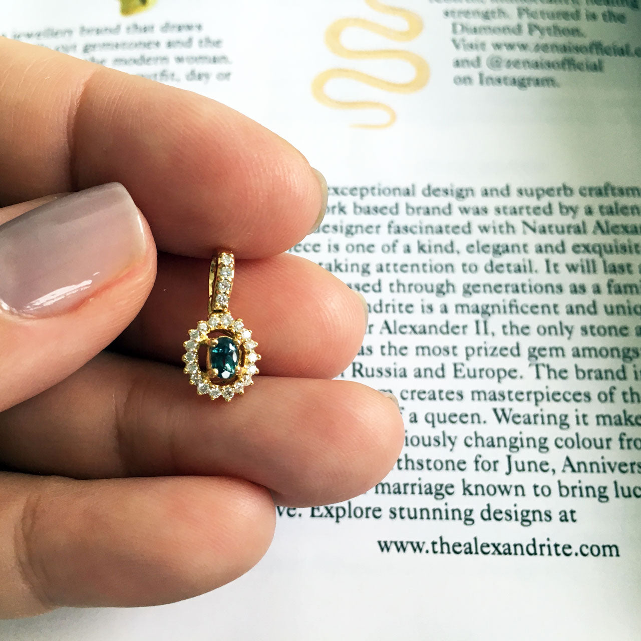 Close-up of a 0.23ct natural alexandrite pendant in 18k yellow gold held by a person
