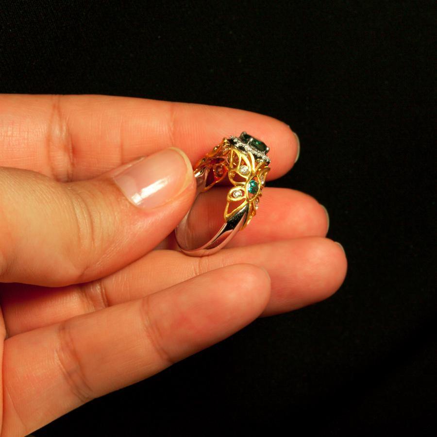 A hand displaying a 0.67ct natural Alexandrite stone in an 18k two-tone gold filigree setting
