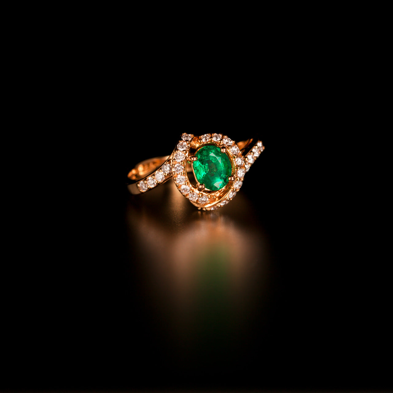 Female hand displaying a 0.56ct natural emerald ring with 18k yellow gold band