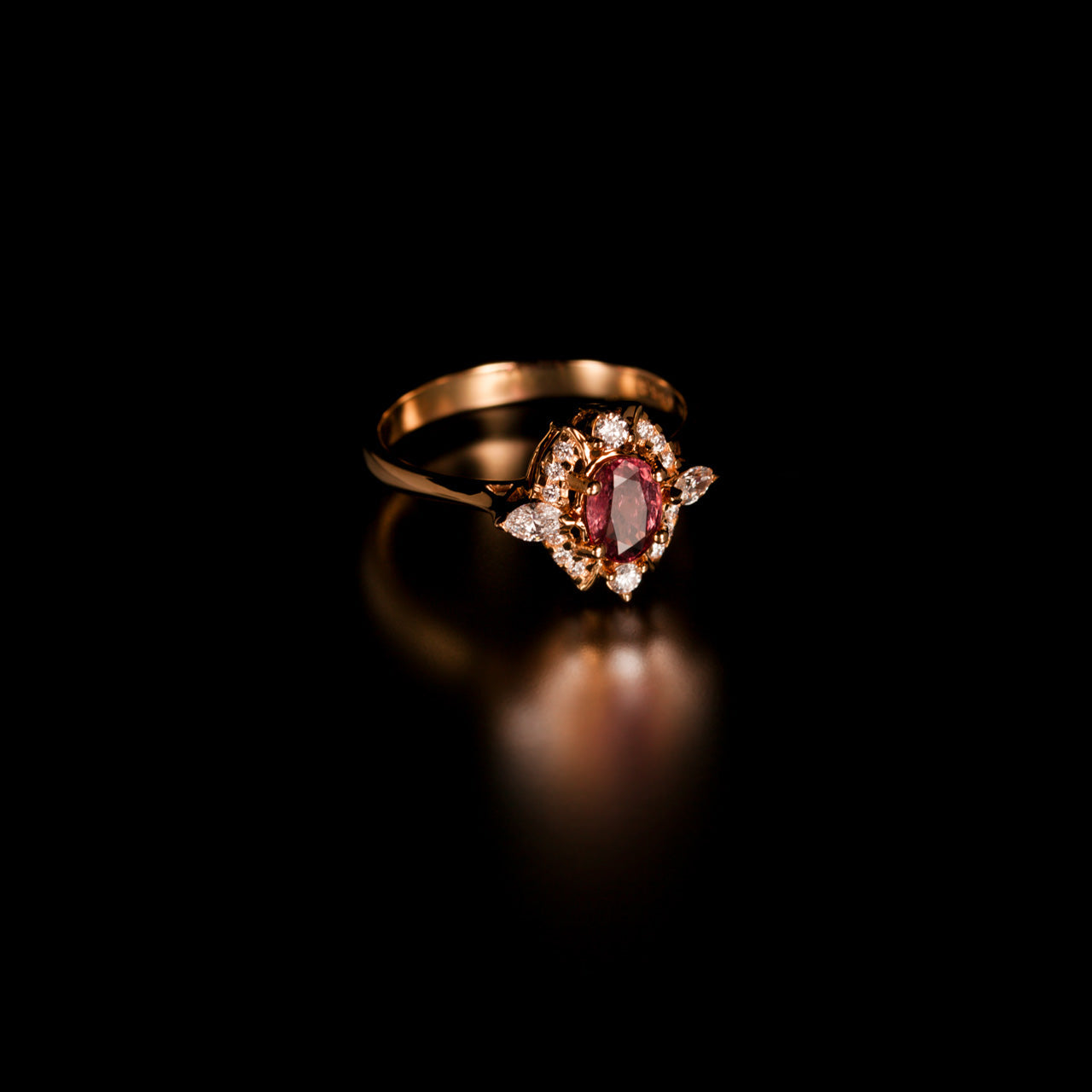 0.76ct natural unheated pink sapphire ring in 18k yellow gold with diamond accents on black background