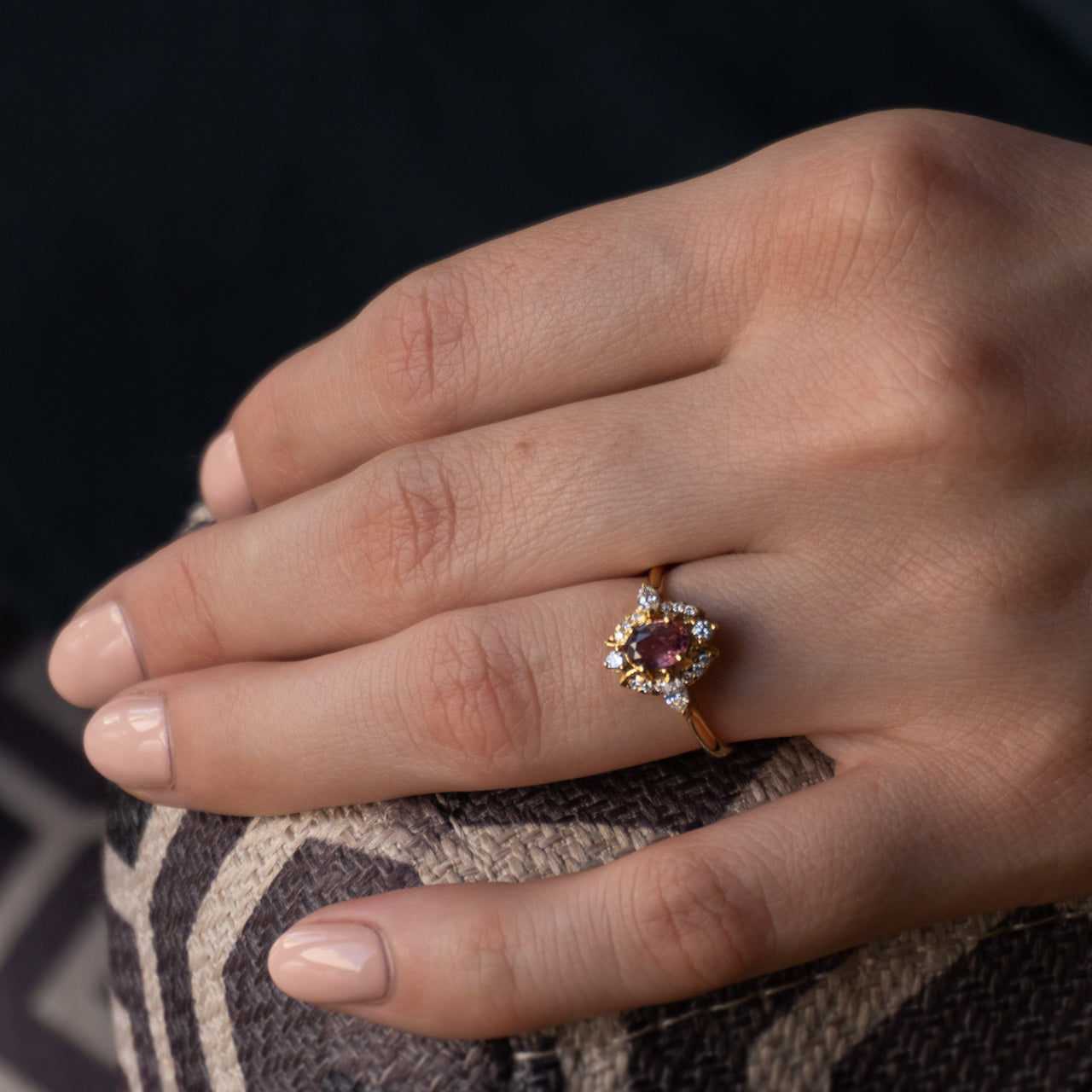 Woman's hand displaying a 0.76ct pink sapphire ring in 18k yellow gold