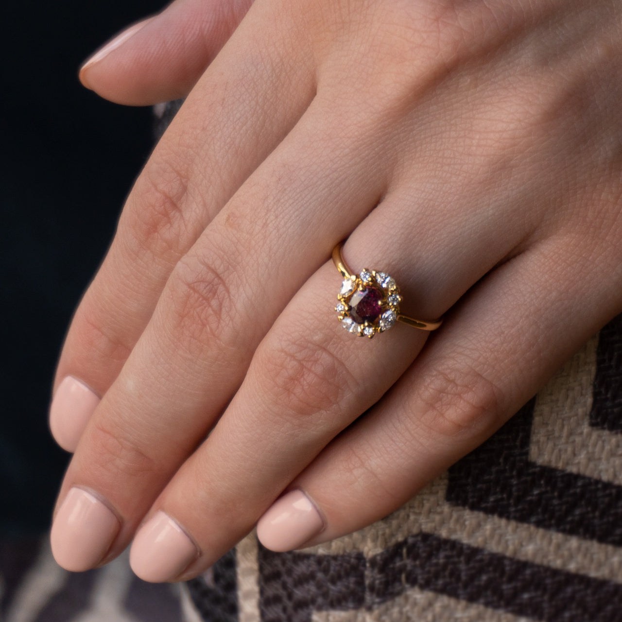 Woman's hand showcasing a 0.82ct ruby ring with diamond details and an 18k yellow gold band