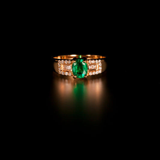 Close-up of 18k yellow gold ring showcasing a 0.64ct natural emerald flanked by diamonds