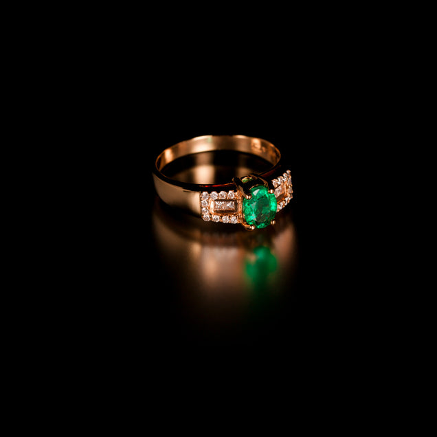 Close-up of 18k yellow gold ring showcasing a 0.64ct natural emerald flanked by diamonds