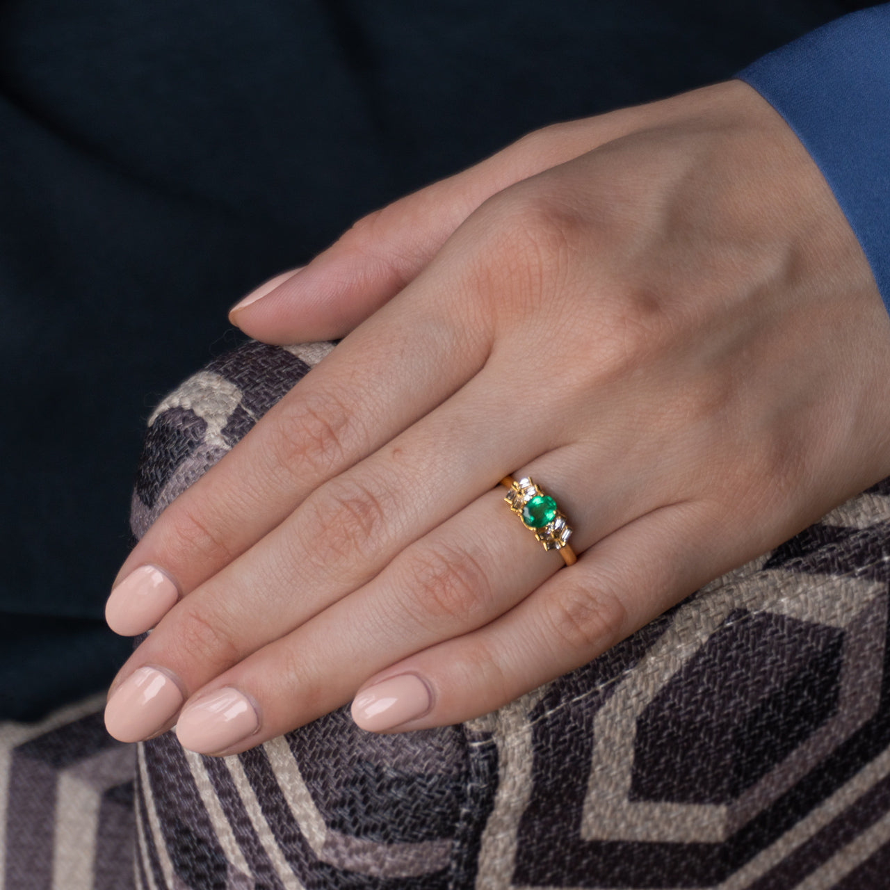 Close-up of a woman's hand holding a 0.63ct emerald 18k yellow gold ring