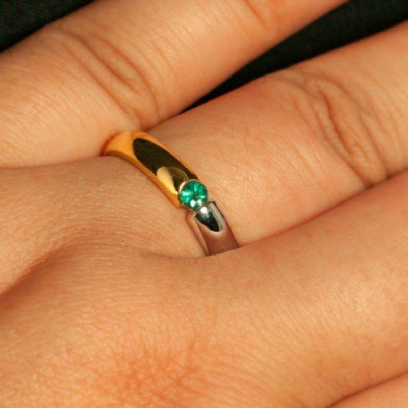 A woman's hand elegantly displaying the 18k gold wedding band with a green alexandrite gemstone